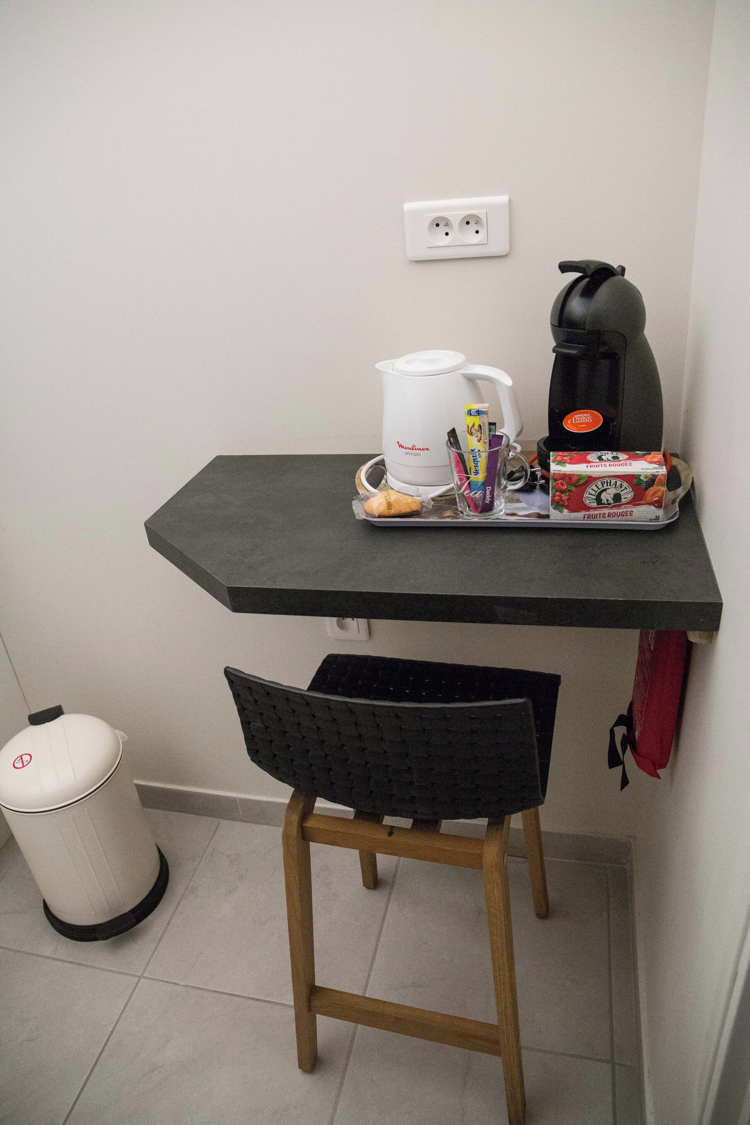 Eine kleine Küchenzeile mit Kaffeemaschine, Wasserkocher und einer Teedose.