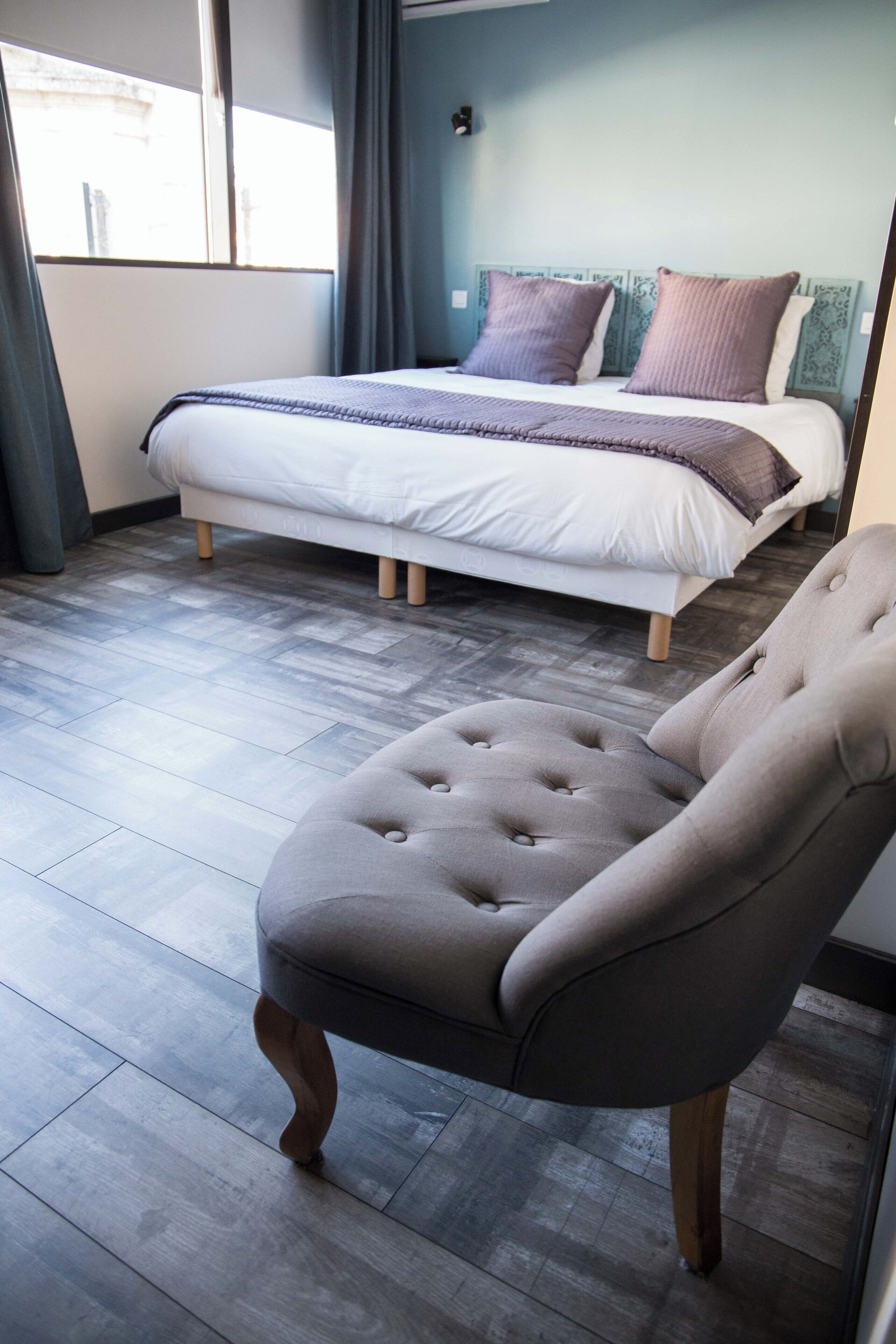 A bedroom with a bed, a chair, and a view of the outside.