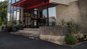 A modern building with a glass facade, a red awning, and a concrete base. - Appart hôtel Chanzy Angoulême Soyaux (Soyaux)
