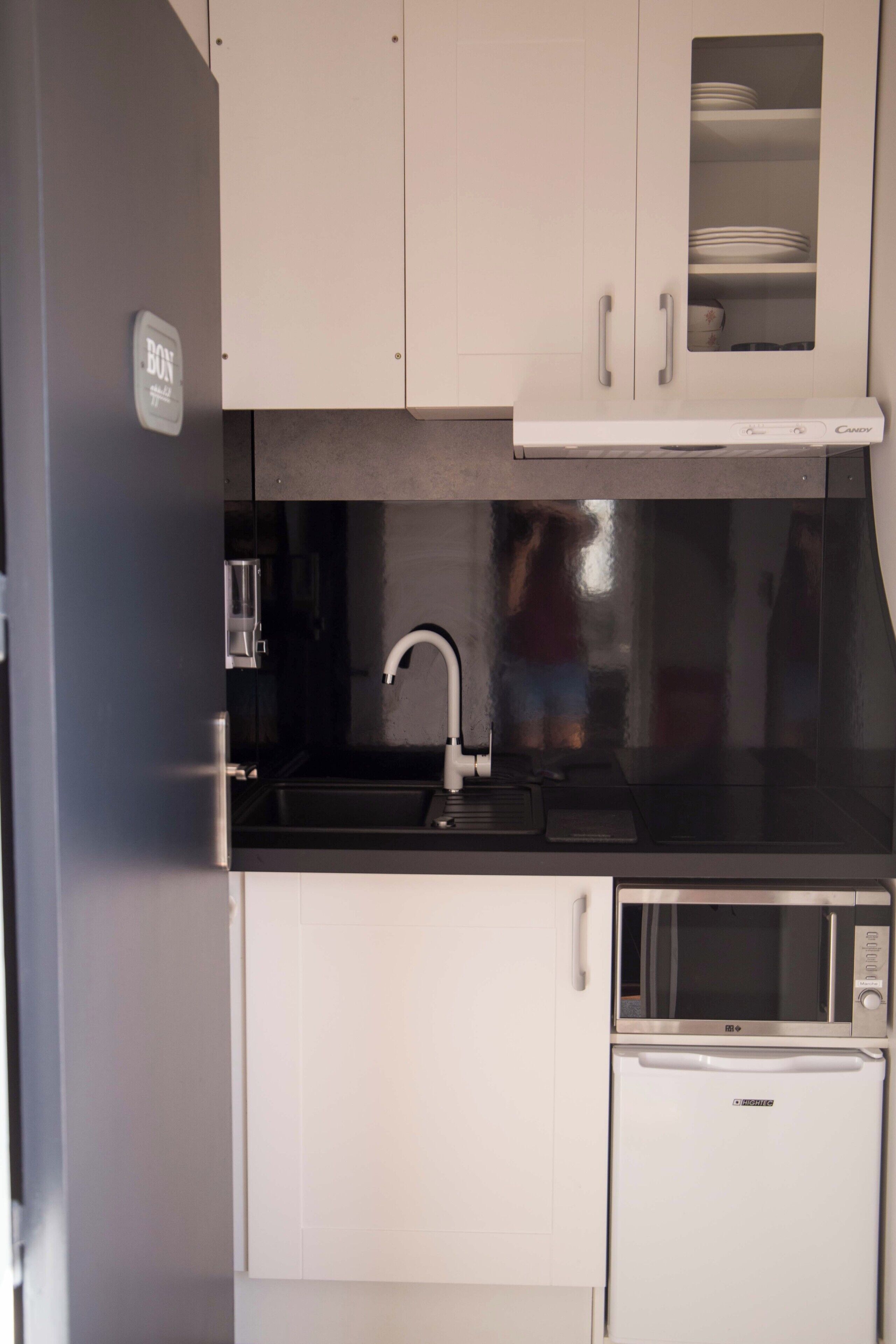 Una cocina compacta equipada con fregadero, microondas y refrigerador.