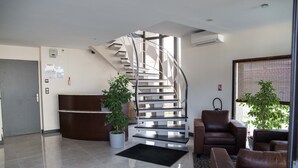 A modern lobby with a spiral staircase, a reception desk, and leather seating area. - Appart hôtel Chanzy Angoulême Soyaux (Soyaux)