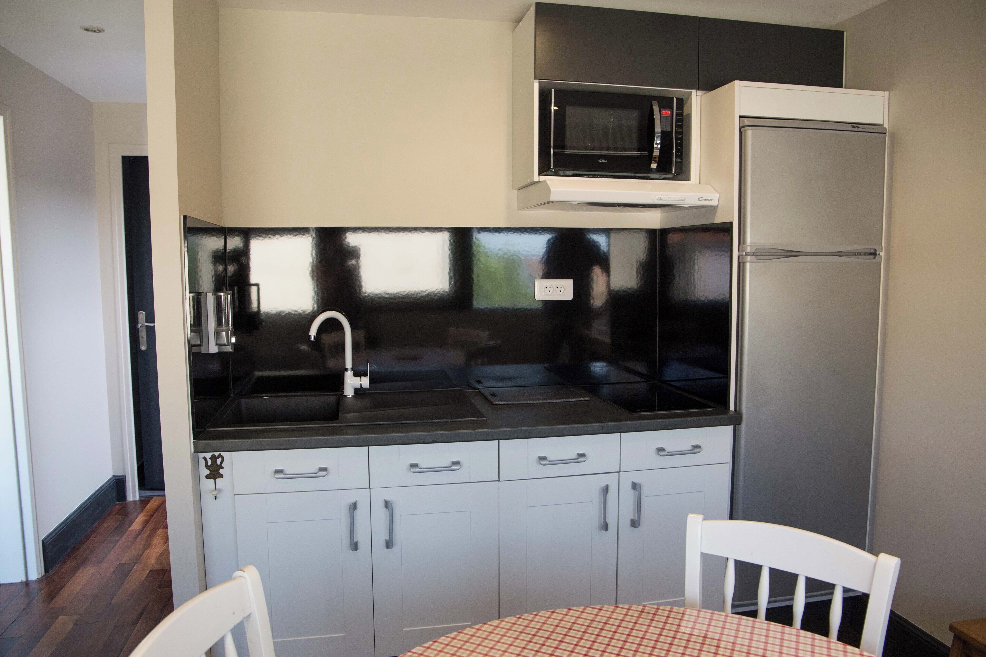 A compact kitchen with a microwave, refrigerator, and a sink.