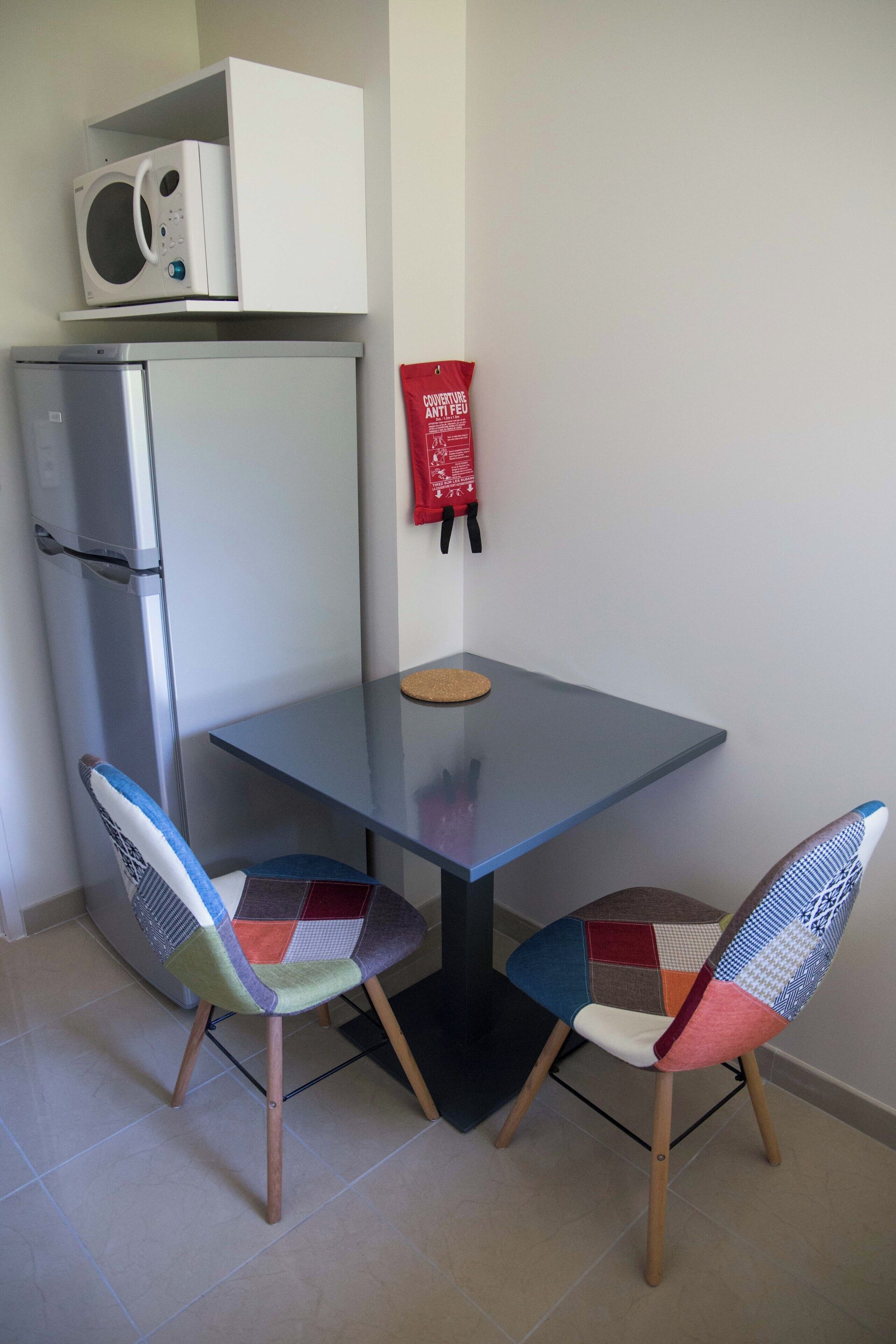 A small kitchenette with a microwave, refrigerator, and a red fire safety poster on the wall.