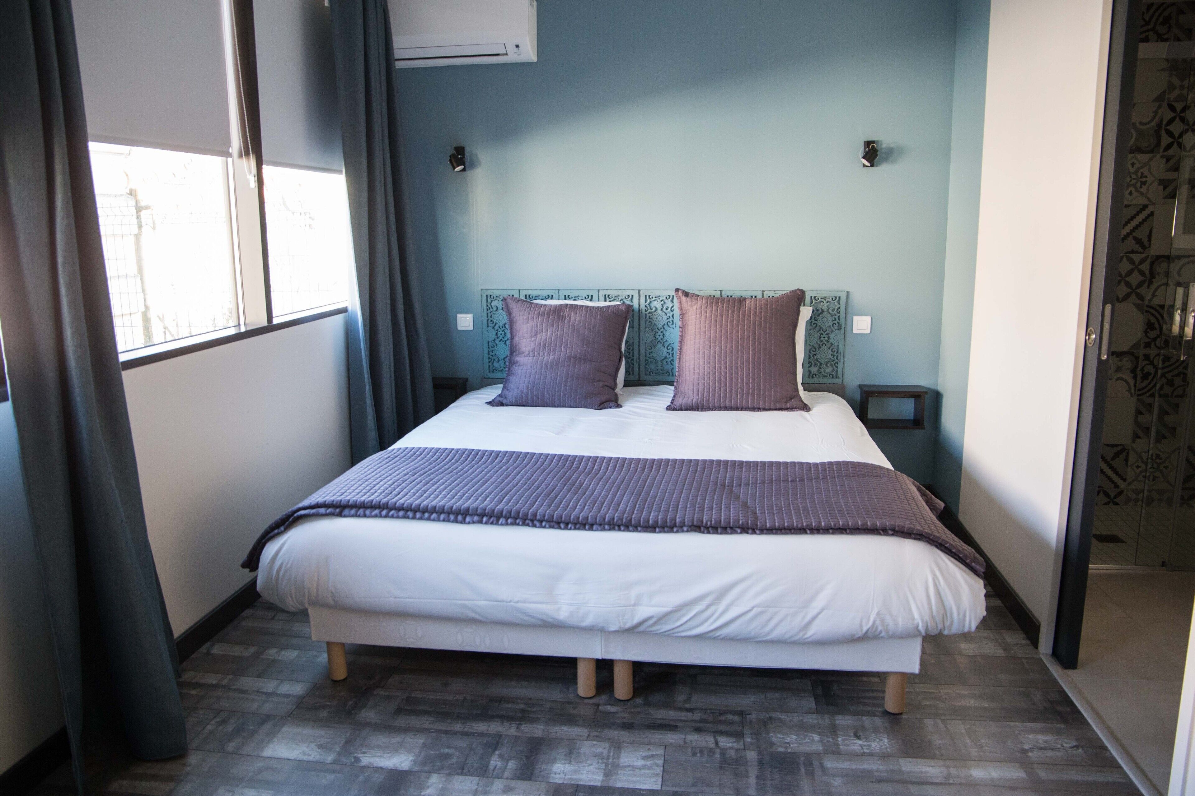Une chambre à coucher avec un lit, des rideaux, une fenêtre et un mur décoré de motifs.