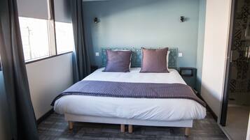 Une chambre à coucher avec un lit, des rideaux, une fenêtre et un mur décoré de motifs.