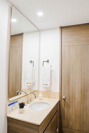 Une salle de bain avec un lavabo, un miroir et une porte en bois.