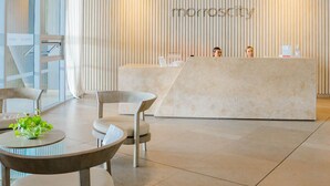 A modern reception area with a central desk, seating, and a glass partition.