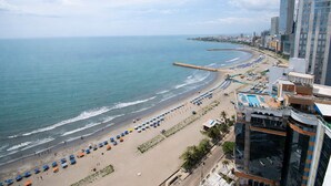 A coastal cityscape with a beach, buildings, and a clear sky.