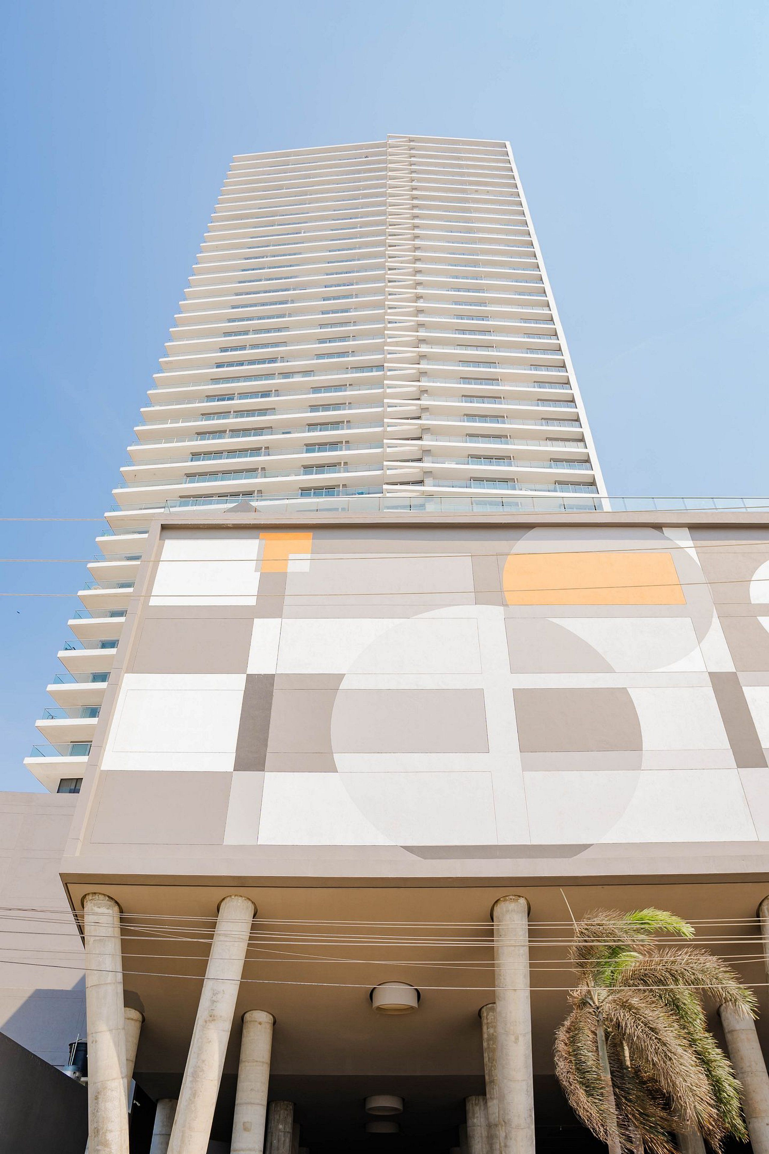 A tall, modern building with a geometric facade and multiple balconies.