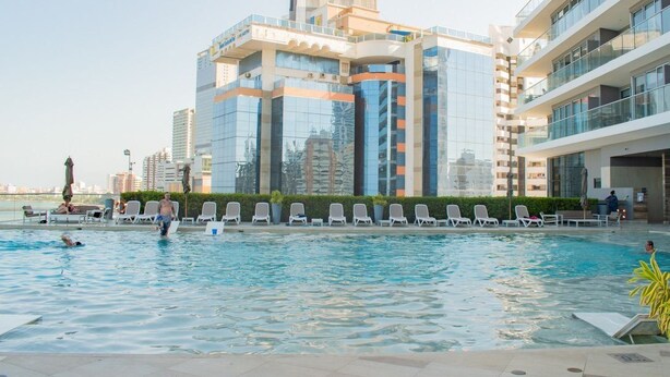 A swimming pool with lounge chairs and a view of modern buildings.