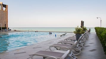 Zona de piscina con sillones de descanso y vista al mar.