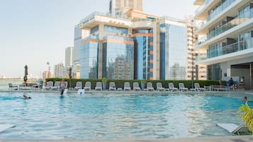 A swimming pool with lounge chairs and a view of modern buildings.