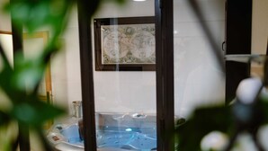 Un bain à remous doté d’une enceinte en verre, entouré de plantes d’intérieur.