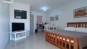 Une chambre à coucher avec un lit, une télévision, un bureau et une chaise.