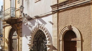 Un edificio histórico con arcos, un balcón con barandilla y una farola.