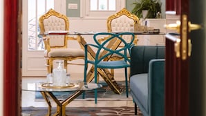 Un comedor con una mesa de vidrio, dos sillas, un sofá y una araña.