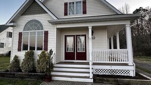 A two-story house with a front porch, a garage, and a brick driveway. - Farmhouse Charm Woolford Studio Apt. w/ Amazing Eastern Shore Sunrise & Sunsets
 (Woolford)