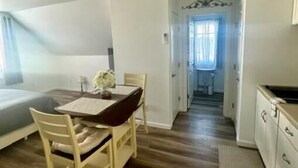A compact room with a dining table, chairs, a bed, and a kitchenette. - Farmhouse Charm Woolford Studio Apt. w/ Amazing Eastern Shore Sunrise & Sunsets
 (Woolford)