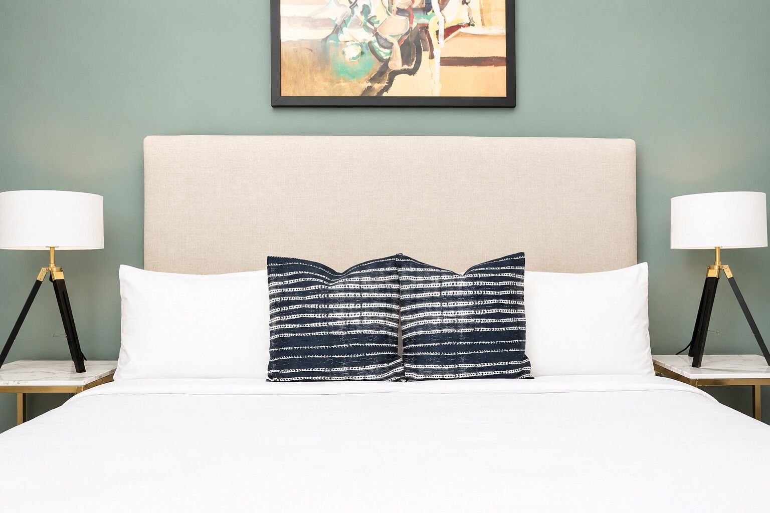 A bed with a white headboard, two bedside lamps, and a patterned pillow.