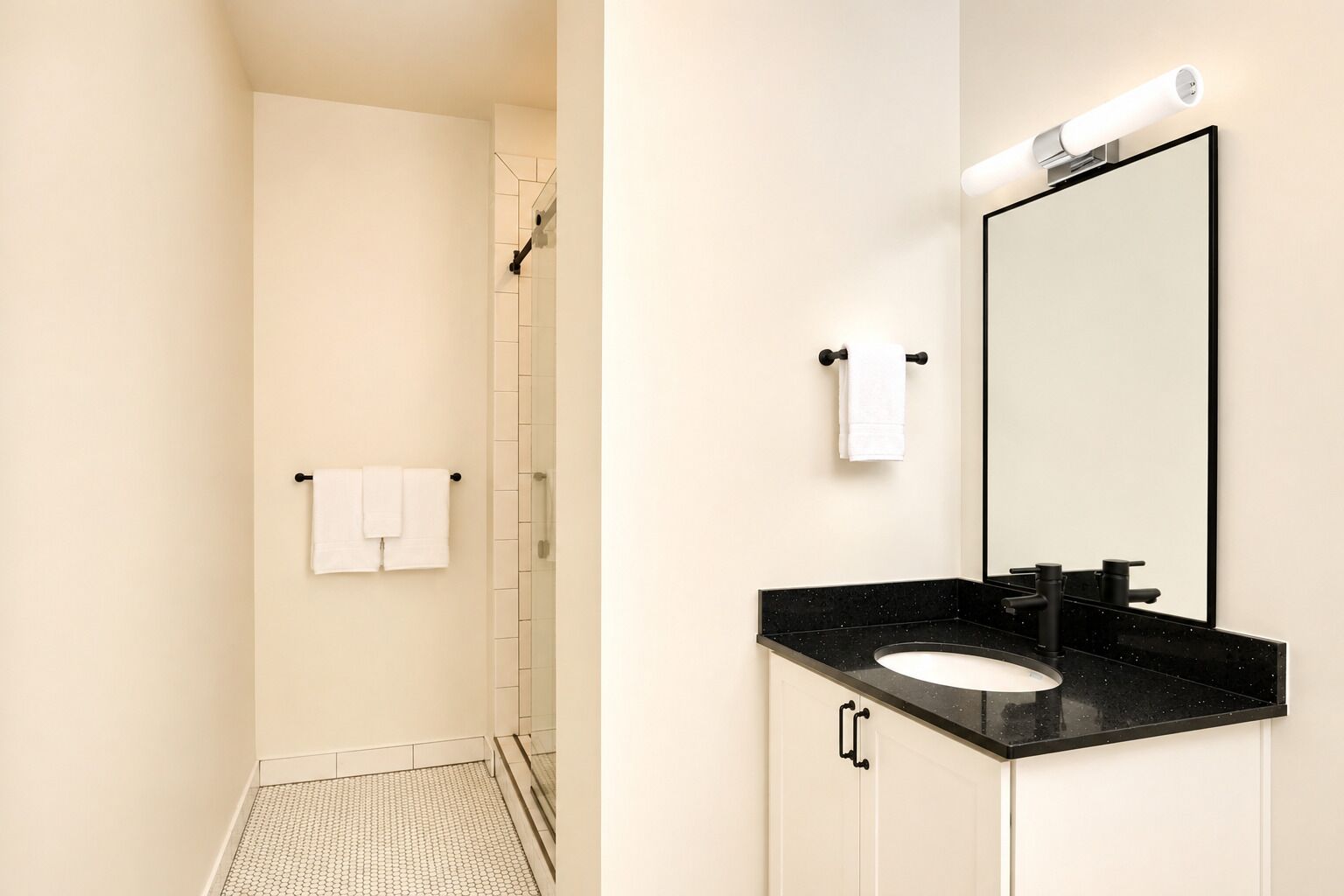 Un baño con lavamanos de superficie negra, espejo y zona de ducha.