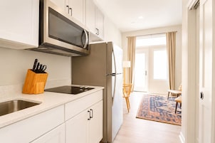 A modern kitchen with a microwave, stove, and refrigerator. There is a wooden utensil holder on the counter.