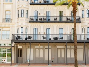 A multi-story building with balconies, a palm tree, and a fire hydrant.
