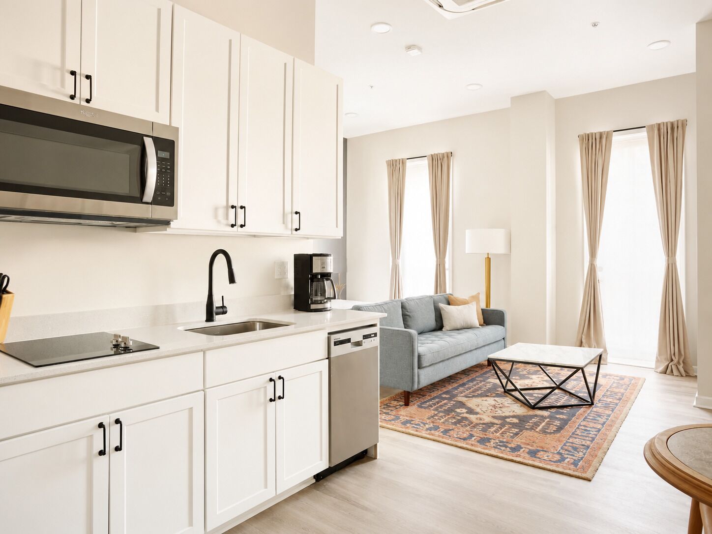 A modern kitchen with white cabinetry, a built-in microwave, and a coffee maker.