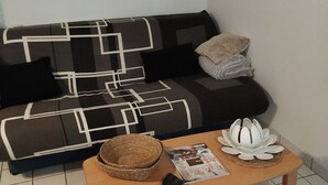 Un salon avec un canapé, une table basse sur laquelle sont posés des magazines et un tableau au mur.