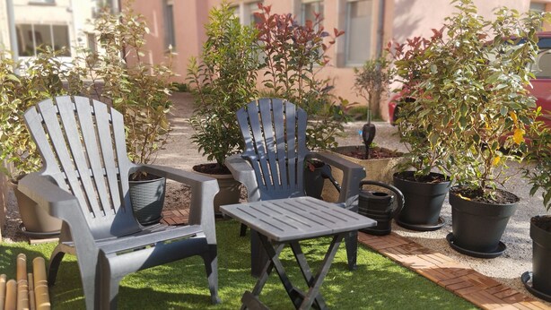 Un espace patio aménagé avec deux fauteuils Adirondack, une petite table et des plantes en pot.