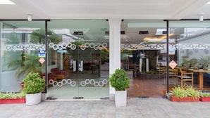 Entrada de hotel con puertas de vidrio, el logotipo de Visa y plantas en macetas.