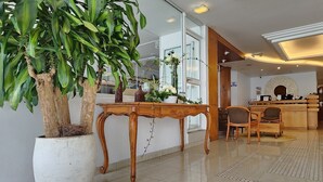 Un interior moderno con una planta grande en maceta, una mesa de madera y un espacio de estar con sillas.