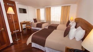 Una habitación de hotel con dos camas, un escritorio, una silla, una lámpara y un teléfono.