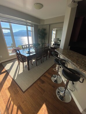 A modern kitchen with a large island, a dining area with a view of the lake, and a large window. - Sunset Waterfront Resort 9. Luxury Lakeside, Lakeview 3 bed/2bath Kelowna Condo. (Kelowna)