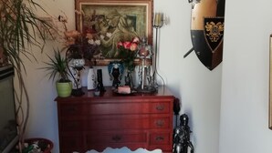 Una taula de console de fusta amb un quadre amb marc, una planta en test i una estàtua decorativa.