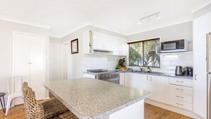 A modern kitchen with white cabinetry, a granite countertop, a built-in oven, a microwave, and a refrigerator.