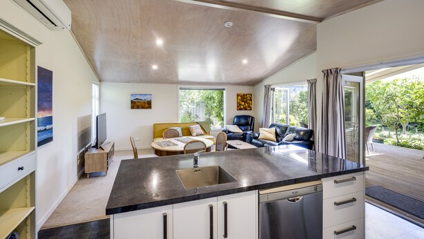 Une cuisine moderne dotée d’un îlot central, un coin repas avec une table et des chaises, et un espace de détente avec un canapé et un téléviseur.
