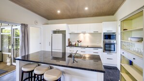Une cuisine moderne dotée d’un îlot central, de meubles blancs et d’appareils électroménagers en acier inoxydable.