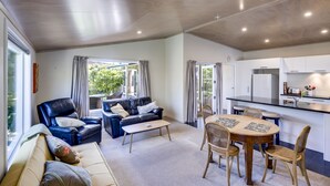 Un salon moderne comprenant un canapé, une table basse et une table à manger avec des chaises. Il y a également un coin cuisine avec un réfrigérateur et un évier.