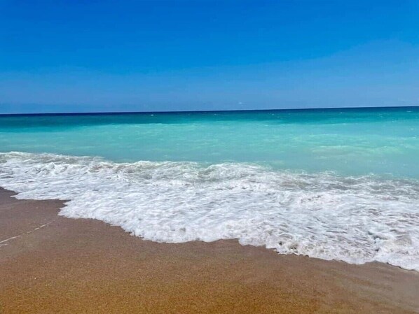 A beach with clear turquoise water and gentle waves.