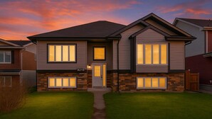 A two-story house with a number 9219 on the front door, a stone facade, and a well-maintained lawn. - Tropical Oasis - King Beds - Garage - Long Stays! (Edmonton)