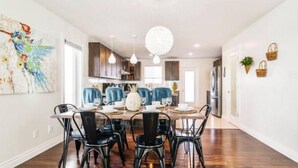 A modern dining area with a wooden table, black chairs, and pendant lighting. - Tropical Oasis - King Beds - Garage - Long Stays! (Edmonton)