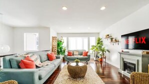 A modern living room with a grey sofa, a coffee table, and a fireplace. - Tropical Oasis - King Beds - Garage - Long Stays! (Edmonton)