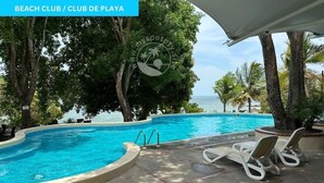 A poolside area with a view of the ocean, lounge chairs, and a covered seating area. - Beach and Golf Escape in your private Luxury Resort Studio in Coronado (Playa Coronado)
