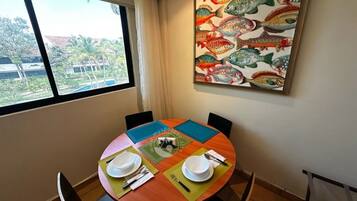 A dining area with a round table, chairs, and a painting of fish on the wall.