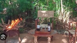 An outdoor seating area with a fire pit, two wine bottles, and a table. - Heaven GetAway lodge  (Arusha)