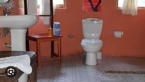 A bathroom with a sink, toilet, and a painting on the wall. - Heaven GetAway lodge  (Arusha)