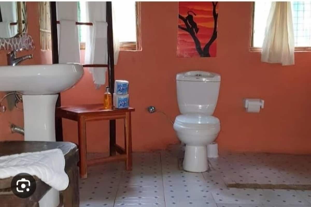 A bathroom with a sink, toilet, and a painting on the wall.