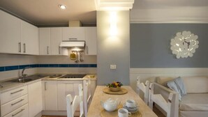 A compact kitchen with white cabinets, a sink, and a dining area with a table set for two. - Tranquil Lantana Resort 2 Bedroom Apartments Sleeps 7 Persons (Pula)