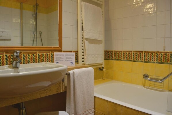Un baño con lavamanos, espejo, ducha y bañera.