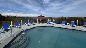 A pool area with blue lounge chairs and a red umbrella. - Acadia Ocean View Hotel (Bar Harbor)